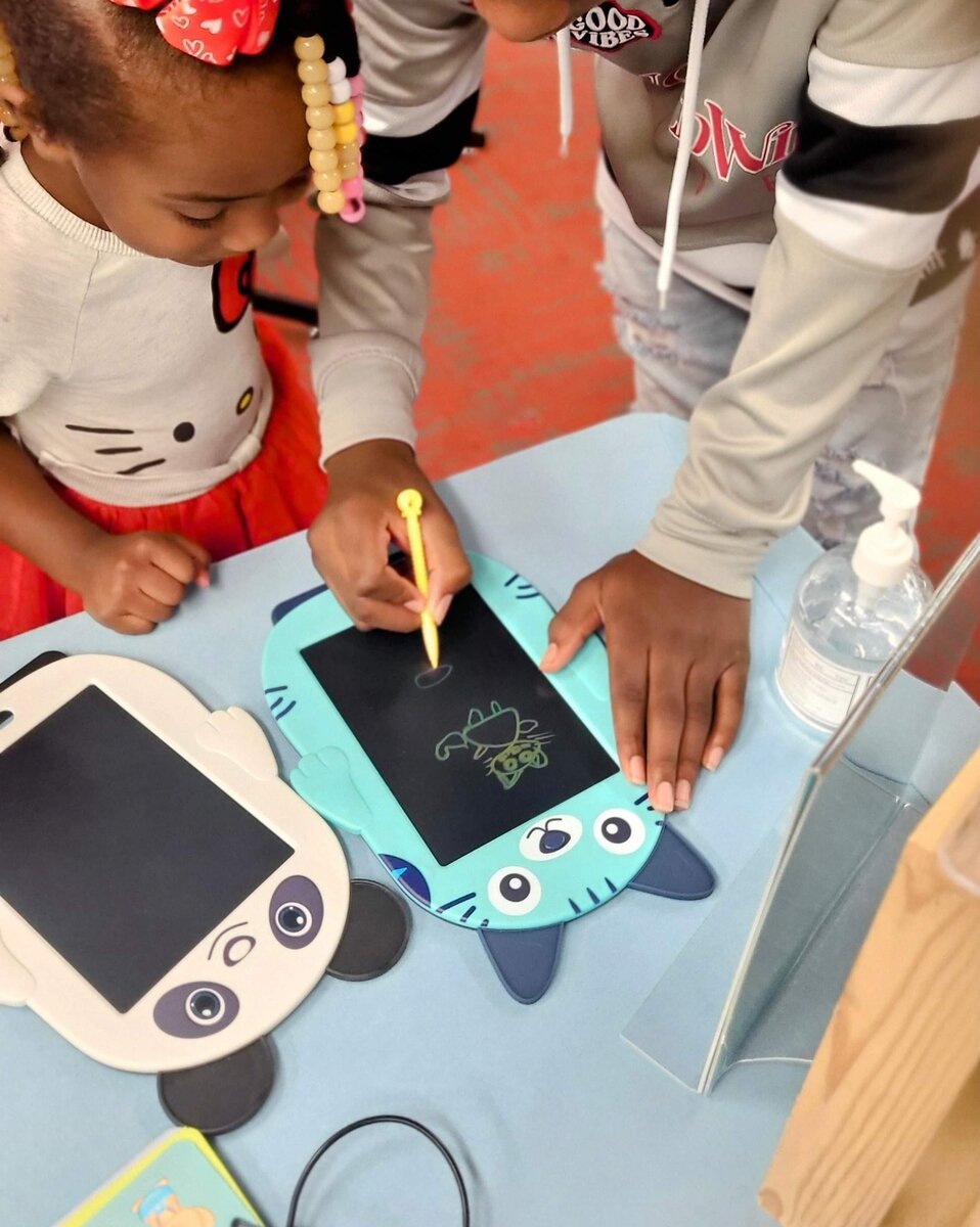 Children using LCD doodle tablets at community event